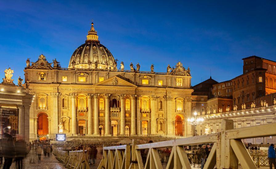 A stunning view of the Vatican City at dusk with the iconic St. Peter's Basilica in the background.